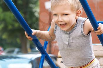 Blond boy with open mouth rides on seesaw