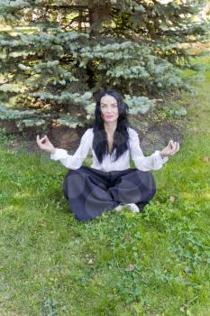 European brunette woman on green grass in yoga pose