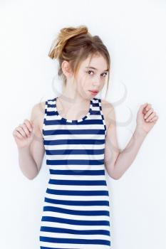 Cute girl eleven years old with blond long hair standing near white wall and upwards hands