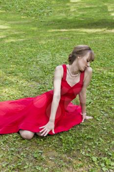 Beautiful lady in red are sittiing on green grass