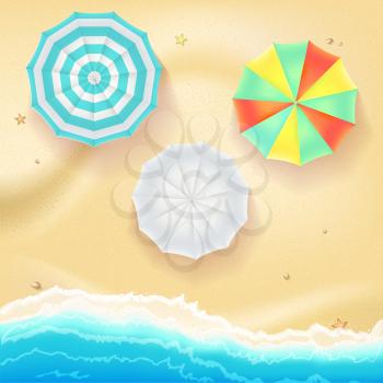 Summer travel background. Sunny sandy beach with colored umbrellas. Tropical seashore with a view of the surf, top view.