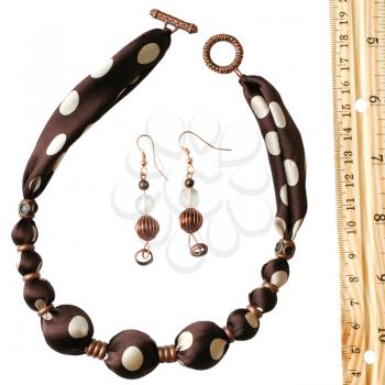 brown polka dot silk beads, earrings and wooden rule isolated on white
