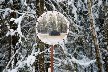 road mirror in winter forest with reflection from car