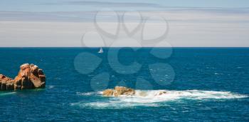view on sea with pink rocks and yacht near Ile de Brehat, Brittany, France
