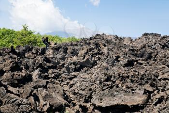 sharp hardened lava rocks close up with Etna on background