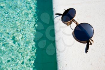 black round sun glasses on pool boardi n summer day