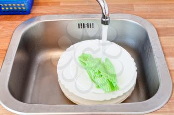 wash-up by dishcloth in metal washbasin in kitchen
