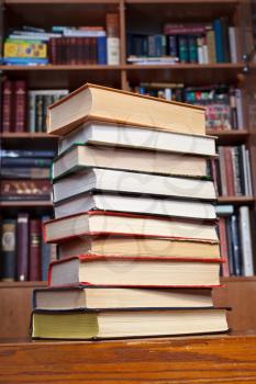 stack of books on wooden table near bookcases