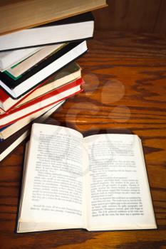 stack of books and open book with blur font on wooden table