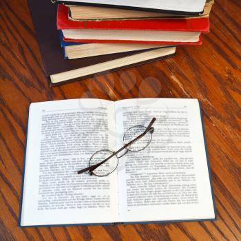 above view of blank open book and eyeglasses on wooden table