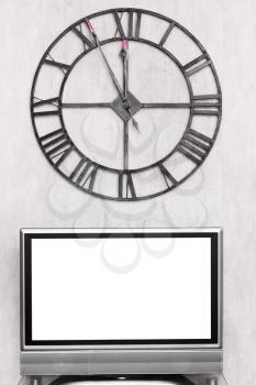 at five minutes to twelve hours on wall clock under blank white screen of TV set