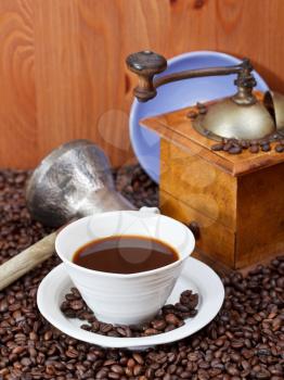 cup of coffee and roasted coffee beans with retro manual mill, coffee pot