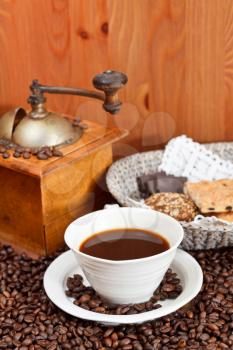 cup of coffee and roasted coffee beans with retro wooden manual mill, biscuit