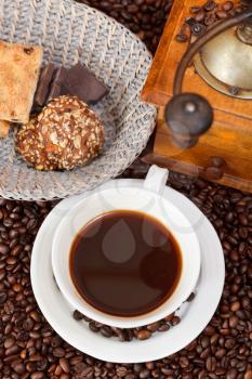 top view cup of coffee and roasted coffee beans with retro wooden manual mill, biscuit, chocolate bars