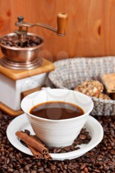 cup of coffee and roasted coffee beans with retro copper manual mill, biscuit, cinnamon