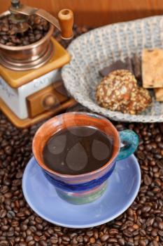 above view mug of coffee and roasted coffee beans with retro copper manual mill, biscuit, chocolate bars