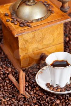 small cup of coffee and roasted coffee beans with retro wooden manual mill, cinnamon