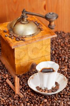 small cup of coffee and roasted coffee beans with retro wooden manual grinder, cinnamon