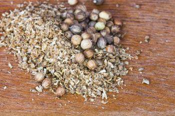 milled coriander spice and dried coriander seeds on wooden board