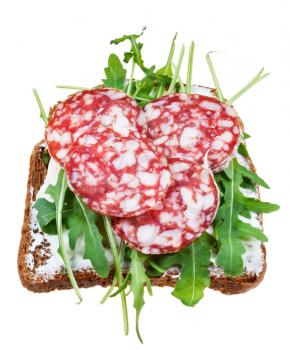 sandwich from salami, grain bread, spread, and fresh arugula isolated on white background