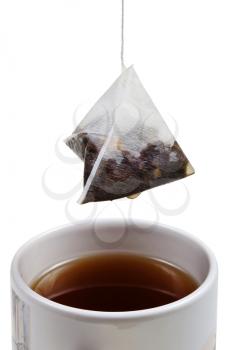 tea bag over brewing tea in cup close up isolated on white background
