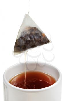 removing of tea bag from cup with brewing tea close up isolated on white background