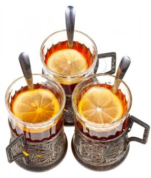 top view of three vintage glasses in silver glass holders with black tea and lemon isolated on white background