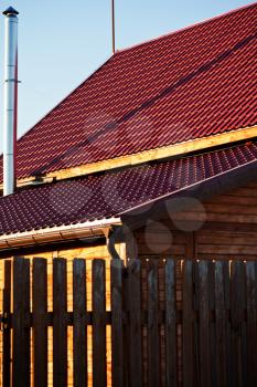 wood fence, chimney,red tile of new wooden house in country village