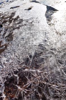 crust of ice on frozen stream in spring morning