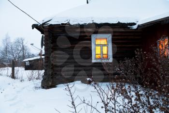 yellow lighting window of rural house at blue winter gloaming