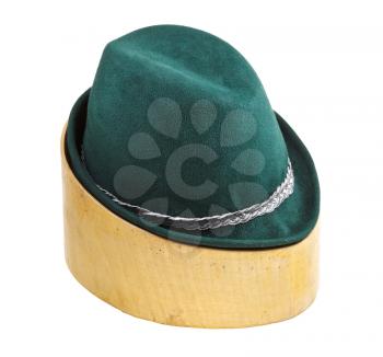 green tyrolean felt hat on linden wooden hat block isolated on white background