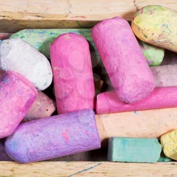 many colored chalks in wooden box close up