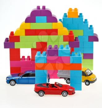 plastic block house and three model cars on white background