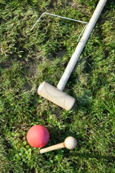 red ball near hoop in game of croquet on green lawn in summer day