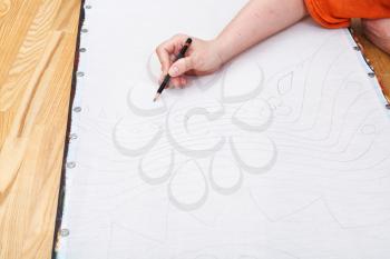 artist draws pencil pattern on silk for cold batik painting