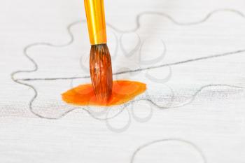 drawing orange ornament on silk canvas with brush close up