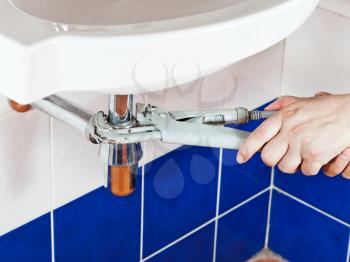 plumber fixing sink siphon by pipe-wrench