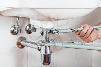plumber repairing sink drain by pipe-wrenches