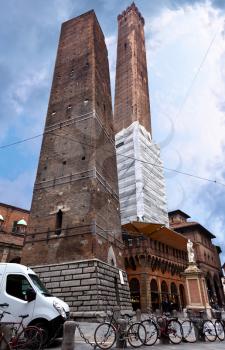 square with two towers and statue of Saint Petronius under cloudy sky in Bologna, Italy