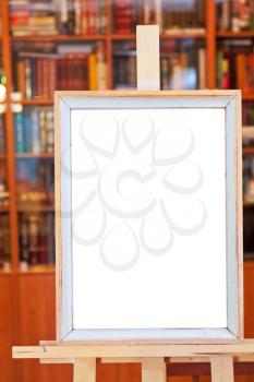 white canvas of simple picture frame on easel with clipping path and home library on background