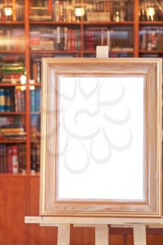white canvas of wide picture frame on easel with clipping path and home library on background