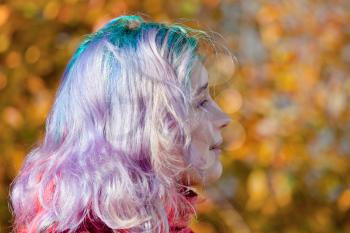 young woman half face with multicoloured streaks hair outdoor in autumn day