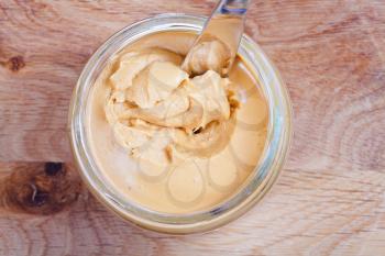 peanut butter and knife in a glass jar on wooden table