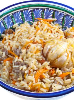 traditional asian pilau with garlic bulb in ceramic bowl close up