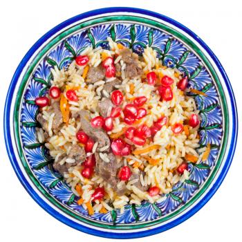 top view on traditional asian pilaf with pomegranate seeds in ceramic bowl isolated on white background