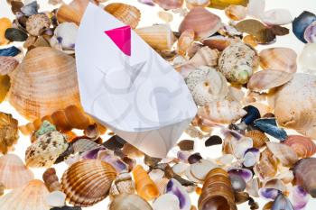 white paper boat on background from sea shells
