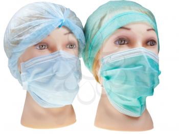 two women's dummy doctor heads wearing textile surgical cap and medical protective mask isolated on white background