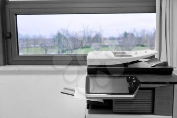 big grey copier in grey office and color life beyond window