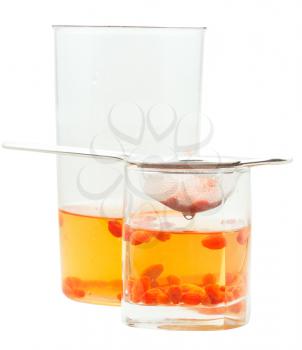 preparing of goji berry tincture - side view of pot and glass with goji berries infusion isolated on white background