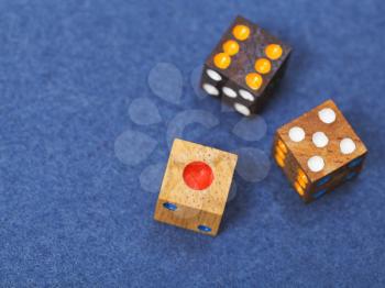 three wooden gambling dices on blue cloth of gaming table